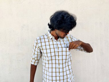 Uzun saçlı genç adam sol eliyle gömleğinin cebini kontrol ediyor. Para yok, para yok.