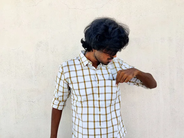 Uzun saçlı genç adam sol eliyle gömleğinin cebini kontrol ediyor. Para yok, para yok.