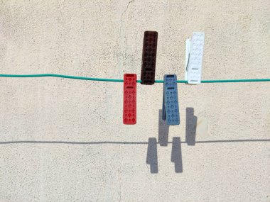 Dört renkli kumaş tokası veya ipte beyaz arkaplanda gölgeler olan plastik mandallar.