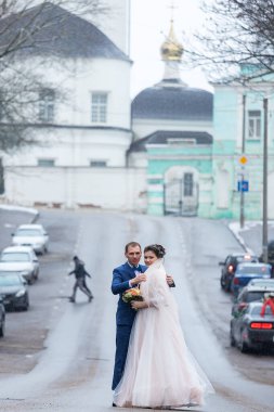 Gelin ve damat kilisenin arka planında, dini âşıklar, kışın düğün yürüyüşü, bir erkek ve bir kadın nazikçe öpüşür ve gülümserler.