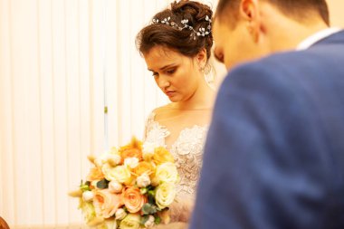 Yeni evliler evlilik belgesini imzalarlar, aşıklar evlilik sözleşmesini doldurur, aile hukuki evraklarını düğünde doldururlar.