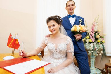 Yeni evliler evlilik belgesini imzalarlar, aşıklar evlilik sözleşmesini doldurur, aile hukuki evraklarını düğünde doldururlar.