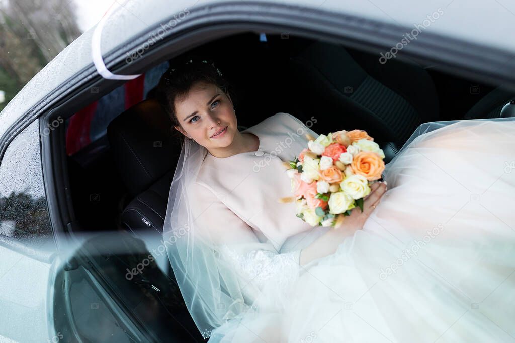 a beautiful bride sits in a wedding car, a young girl in a white dress with a bouquet of flowers goes on a date with a loved one, the newlyweds go on a wedding trip