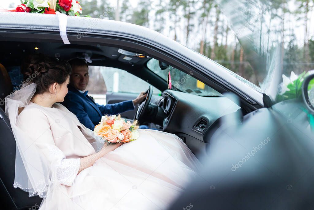 the bride and groom are sitting in a car decorated with flowers, the wedding cortege at the wedding ceremony, two happy people are going to get married