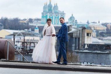 Gelin ve damat kilisenin arka planında, dini âşıklar, kışın düğün yürüyüşü, bir erkek ve bir kadın nazikçe öpüşür ve gülümserler.