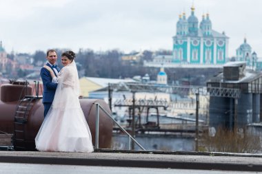 Gelin ve damat kilisenin arka planında, dini âşıklar, kışın düğün yürüyüşü, bir erkek ve bir kadın nazikçe öpüşür ve gülümserler.