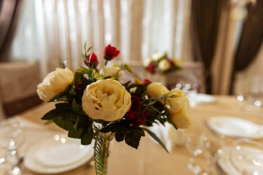 Düğünde çiçekli süslemeler, restoranın iç dekorasyonu bayram için dekoratör tarafından hazırlandı, masadaki vazolarda güzel taze çiçekler, misafirlerin hediyesi olarak bir buket çiçek.