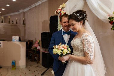 Beyaz elbiseli güzel bir gelin elinde bir buket çiçek tutar. Düğün geleneği kızlara buket atmaktır. Taze çiçekler yeni evlilere mutluluk getirir.