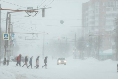 Zorlukla yürüyen bir adam, yoğun bir kar yağışı sonrası kaldırımda kar yağışı yapar. Kışın kamu hizmetlerinin kötü işleyişi