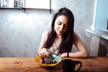 Kız masada oturmuş tatlı bir tatlı yiyor. yüksek kalorili kahvaltı