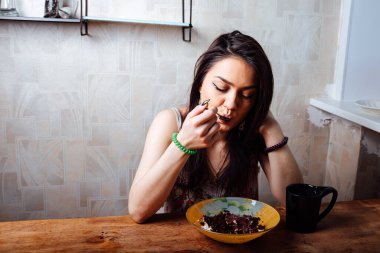 Kız masada oturmuş tatlı bir tatlı yiyor. yüksek kalorili kahvaltı