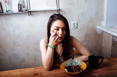 Kız masada oturmuş tatlı bir tatlı yiyor. yüksek kalorili kahvaltı