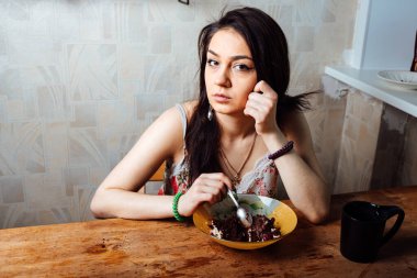 Kız masada oturmuş tatlı bir tatlı yiyor. yüksek kalorili kahvaltı