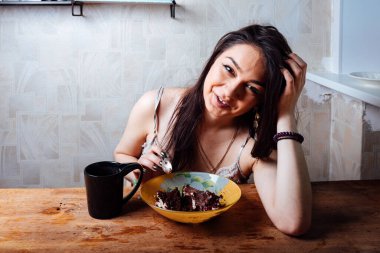 Kız masada oturmuş tatlı bir tatlı yiyor. yüksek kalorili kahvaltı