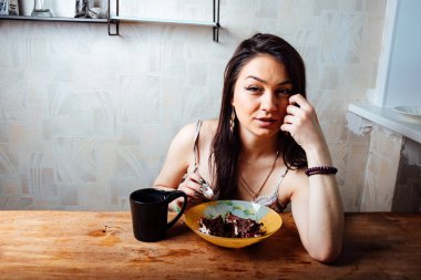 Kız masada oturmuş tatlı bir tatlı yiyor. yüksek kalorili kahvaltı