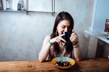 Kız masada oturmuş tatlı bir tatlı yiyor. yüksek kalorili kahvaltı