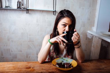 Kız masada oturmuş tatlı bir tatlı yiyor. yüksek kalorili kahvaltı