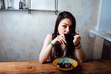 Kız masada oturmuş tatlı bir tatlı yiyor. yüksek kalorili kahvaltı