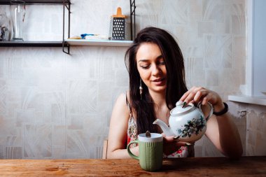 Kız evde kahvaltı yapıyor. Bardaktan sıcak kahve iç.