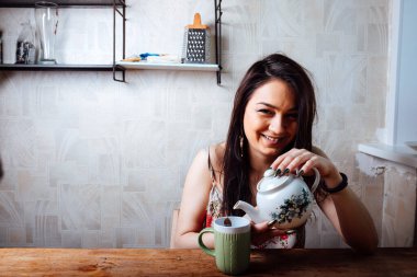 Kız evde kahvaltı yapıyor. Bardaktan sıcak kahve iç.