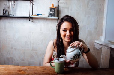 Kız evde kahvaltı yapıyor. Bardaktan sıcak kahve iç.