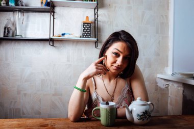 Kız evde kahvaltı yapıyor. Bardaktan sıcak kahve iç.