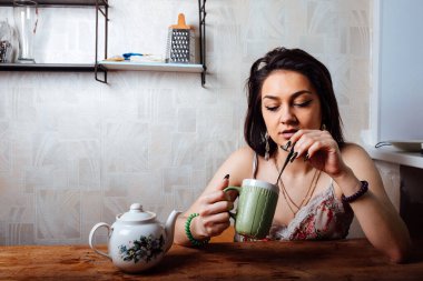 Kız evde kahvaltı yapıyor. Bardaktan sıcak kahve iç.