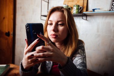 Şaşırmış kız telefondaki müfettişi dinliyor, eliyle başını tutuyor.