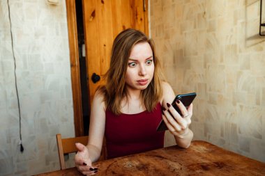 Şaşırmış kız telefondaki müfettişi dinliyor, eliyle başını tutuyor.