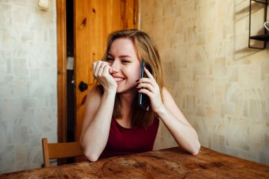 Kız telefonda konuşurken gülüyor.