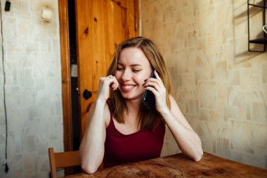 Kız telefonda konuşurken gülüyor.