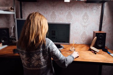 Bir kız klavyede daktilo kullanıyor, evden kişisel bir bilgisayarda çalışıyor, bir adam iki monitörün önünde oturuyor.