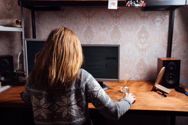 Bir kız klavyede daktilo kullanıyor, evden kişisel bir bilgisayarda çalışıyor, bir adam iki monitörün önünde oturuyor.