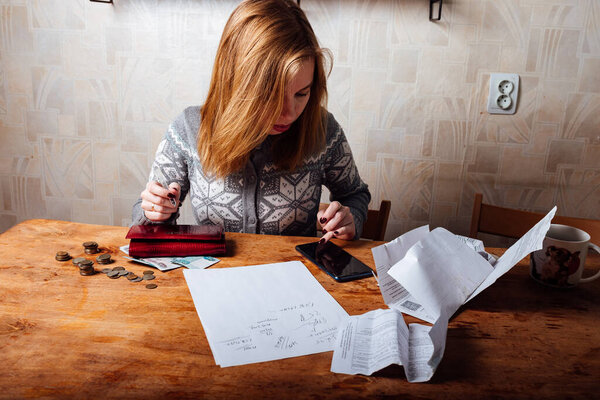 падение доходов и финансовый кризис. высокие счета за квартиру и коммунальные услуги. уставшая девушка заполняет налоговые декларации