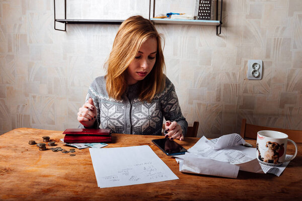 падение доходов и финансовый кризис. высокие счета за квартиру и коммунальные услуги. уставшая девушка заполняет налоговые декларации