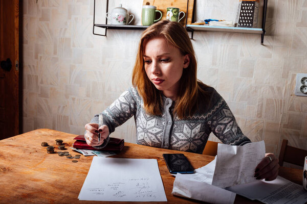 падение доходов и финансовый кризис. высокие счета за квартиру и коммунальные услуги. уставшая девушка заполняет налоговые декларации