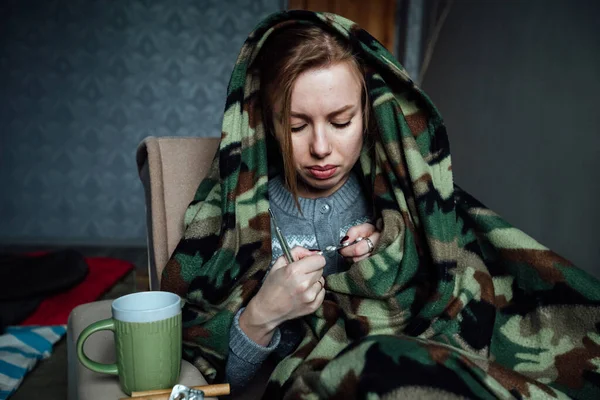 the sick girl drinks pills, measures her temperature and drinks hot tea. to be treated at home due to poor health during the virus epidemic