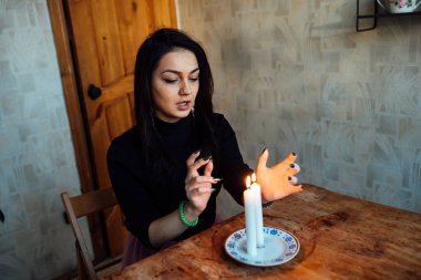 Falcı, bir mum alevine bakar. Geleceği görmek için büyülü bir ayin.