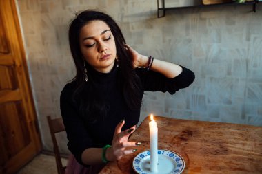 Falcı, bir mum alevine bakar. Geleceği görmek için büyülü bir ayin.