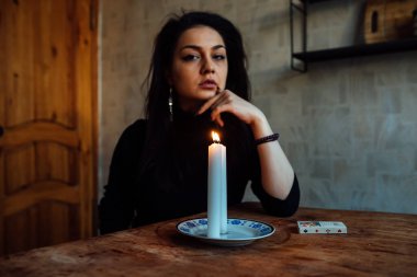 Falcı, bir mum alevine bakar. Geleceği görmek için büyülü bir ayin.