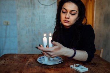 Falcı, bir mum alevine bakar. Geleceği görmek için büyülü bir ayin.