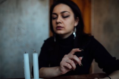 Geleceği tahmin eden bir seanstan sonra falcı ayin mumlarını üfler.