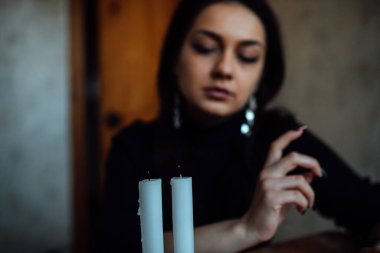 Geleceği tahmin eden bir seanstan sonra falcı ayin mumlarını üfler.