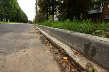 Yol boyunca kırık kaldırım. Kaldırımın tamiri. Çatlak beton döşemeler ve düşük kalite malzemeler. Yol işçilerinin yozlaşması