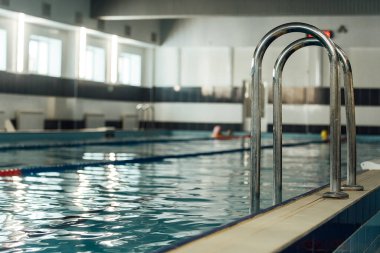 Havuzdan çıkmak için tırabzanlar. Rahatlama ve spor eğitimi için yüzme havuzunda serin ve temiz su