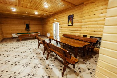 Tahta masa ve saunada sandalyeler. Dinlenmek ve dinlenmek için soyunma odası ve buhar odası. Rahatlama ve kaplıca tedavisi için bir kır evi.