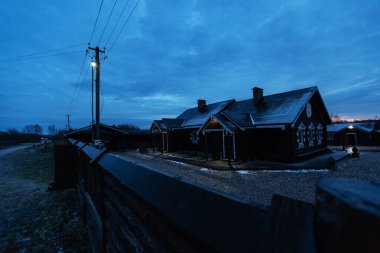 Pencerelerinde kepenkleri oyulmuş güzel bir ahşap kulübe. Ahşap bir çitin arkasından özel bir evin dış görünüşü