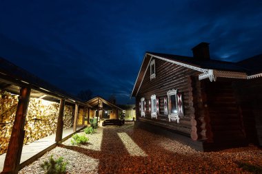 Geceleri ahşap kulübe. Geleneksel Avrupa evleri tarzında güzel bir kır oteli ışıklandırması. Pencerelerden gelen rahat ışık