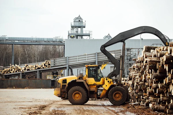 stock image front loader for loading timber. an industrial tractor transports felled wood. wood processing plant. loading of timber to the warehouse