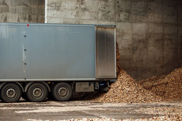 the truck unloads tons of wood waste. sawdust and shavings are stored for further processing. mountain of waste wood